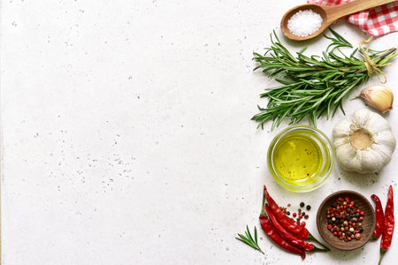 Traditional spices of mediterranean cuisine: sea salt, garlic, pepper, rosemary, sea salt and olive oil on a light slate, stone or concrete background. Top view with copy space.の写真素材