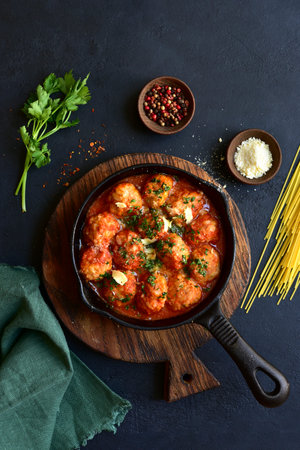 Meatballs with rice in tomato sauce in a skillet pan on dark slate, stone or concrete background. Top view with copy space.の写真素材