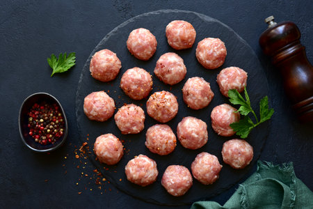 Homemade raw meatballs over dark slate, stone or concrete background. Top view with copy space.の写真素材