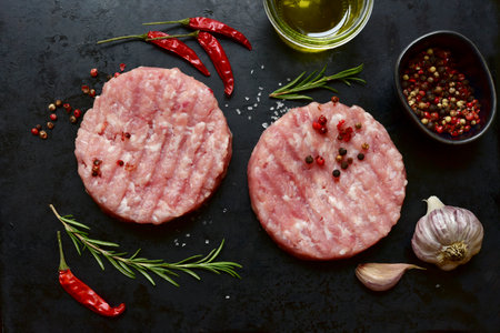 Meat burgers with ingredients for cooking on a black metal tray. Top view with copy space.の写真素材