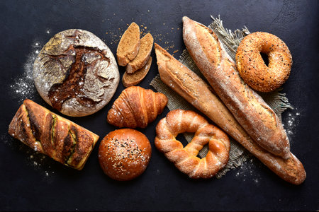 Homemade fresh baked bread with flour and ears on a black background. Top view with copy space.の写真素材