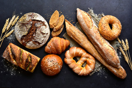 Homemade fresh baked bread with flour and ears on a black background. Top view with copy space.の写真素材