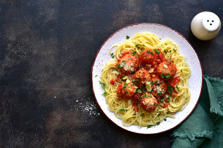 Spaghetti pasta with meatballs in tomato sauce on a plate over dark slate, stone or concrete background. Traditional dish of Italian cuisine. Top view with copy space.の写真素材