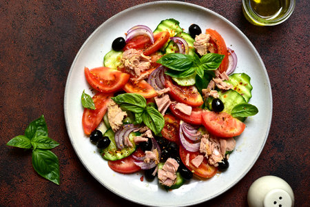 Fresh vegetable salad with tuna on a plate over dark slate, stone or concrete background. Top view with copy space.の写真素材