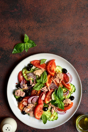Fresh vegetable salad with tuna on a plate over dark slate, stone or concrete background. Top view with copy space.の写真素材