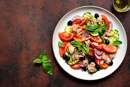 Fresh vegetable salad with tuna on a plate over dark slate, stone or concrete background. Top view with copy space.の写真素材