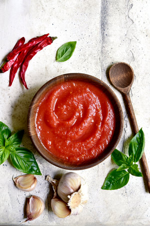 Homemade spicy tomato sauce with ingredients for making on a light slate, stone o concrete background. Top view with copy space.の写真素材