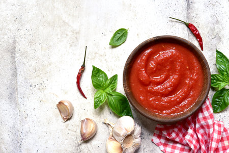 Homemade spicy tomato sauce with ingredients for making on a light slate, stone o concrete background. Top view with copy space.の写真素材