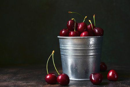 Fresh ripe organic cherry in a metal bucket on a dark slate, stone or concrete background.の写真素材