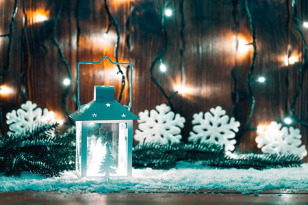 Christmas candle lantern and Christmas tree branches, snow, snowflake and decorations on bokeh...