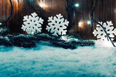 Christmas background with garland, Christmas tree branches, snow and decorations on wooden tableの写真素材