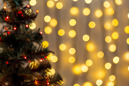 Gold Christmas background of de-focused lights garland with decorated tree