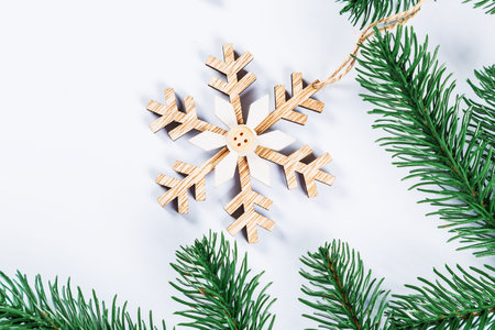 Christmas frame with the branches of the Christmas tree and wooden decorations on white background. Simple Christmas composition with free spaceの写真素材