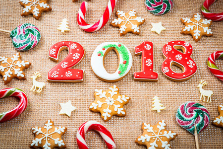 Christmas gingerbread cookies snowflakes and 2018 with candy on burlap background with copy space....