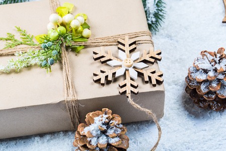 Christmas frame with gift, the branches of the Christmas tree and wooden decorations on snow background. Simple Christmas compositionの写真素材