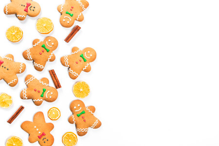 Christmas gingerbread men with lemon and cinnamon sticks on white background.