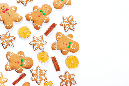Christmas gingerbread men and snowflakes with lemon and cinnamon sticks on white background.