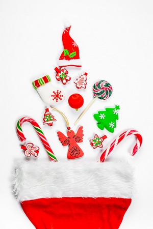 Christmas background with a santa hat from which scattered gifts, candy, New Year decorations toys on a white background.の写真素材