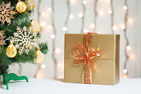 A Christmas tree decorated snowflakes and a garland with gift box on the background of a bokeh and white boards.の写真素材