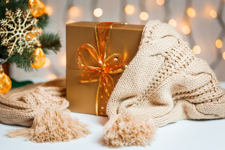 A Christmas tree decorated snowflakes and a garland, gift with knitted scarf on the background of a...