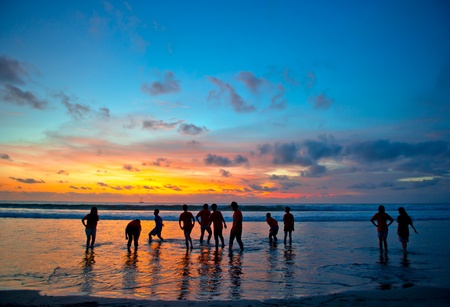 silhouettes of young people at famous sunset beach in Kuta, Bali, Indonesiaの写真素材
