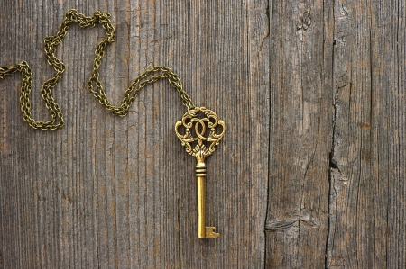 antique golden key over dirty vintage wooden backgroundの写真素材