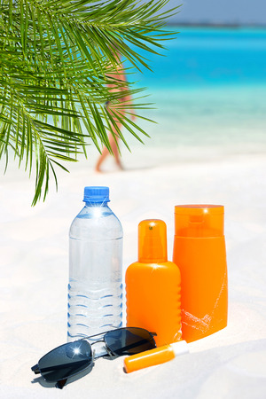sunglasses, water and sun protection cream on the beach backgroundの写真素材