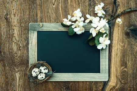 chalkboard with apple tree blossom and easter eggs decoration on rustic wooden backgroundの写真素材