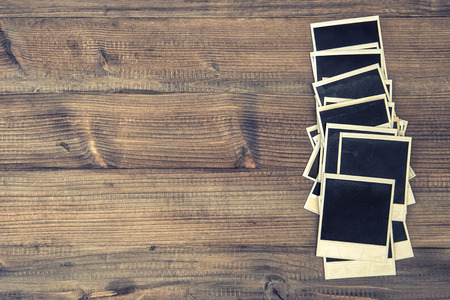 old instant photo frames on rustic wooden background. retro style toned pictureの写真素材