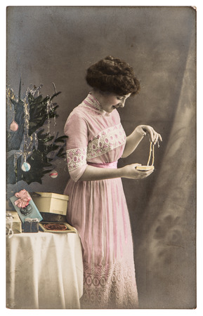 young woman with gifts and christmas tree. vintage picture with original scratches, film grain and blurの写真素材