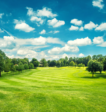 Golf field and blue cloudy sky. Beautiful landscape with green grass. Retro style toned pictureの写真素材
