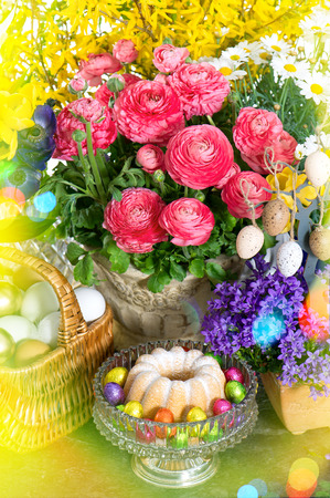 Spring flowers with easter cake and eggs decoration. Retro style toned picture with light leaksの写真素材