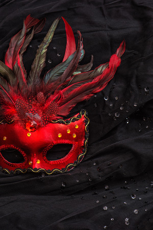 Red venetian carnival mask with feather over black backgroundの写真素材