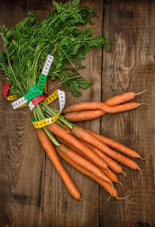 Carrots with measurement tape on wooden background.の写真素材