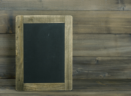Chalkboard on wooden textured background. Vintage style toned pictureの写真素材