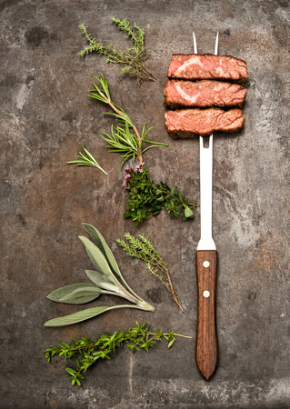 Grilled beef meat with herbs and spices on metal kitchen desk.の写真素材