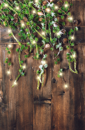 Christmas tree branches hanging over rustic wooden background. Vintage style decoration with magic lightsの写真素材