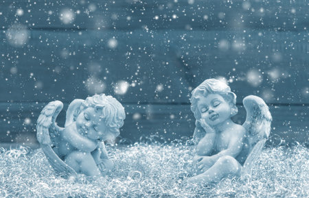 Slipping guardian angel. Christmas decoration. Vintage style blue toned picture with falling snow effect. Selective focusの写真素材