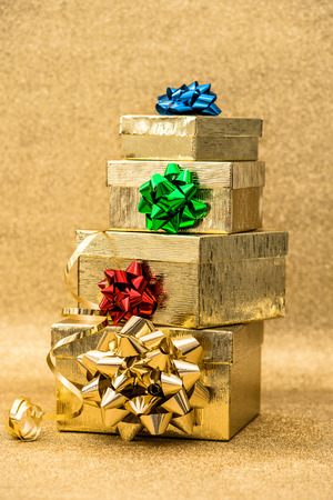 Golden gift boxes with ribbon bow on bright shiny background. Colorful holidays decorationの写真素材