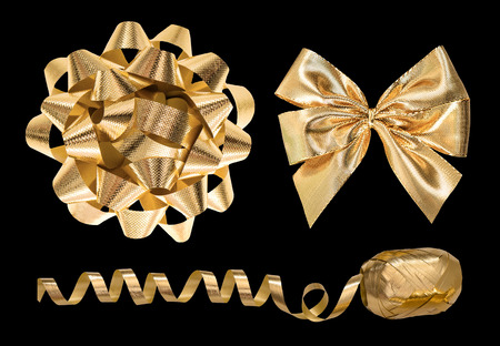 Golden gift decoration objects. Ribbon bow and streamer isolated on black backgroundの写真素材