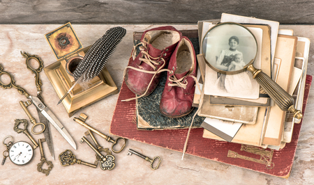 Antique books and photos, keys and writing accessories. Nostalgic still life with baby shoesの写真素材
