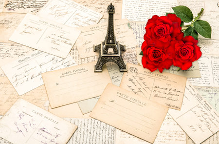 Red roses, old letters and souvenir Eiffel Tower from Paris. Nostalgic holidays background
