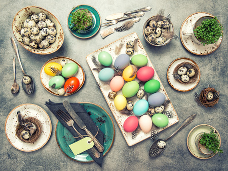 Easter decoration. Festive table place setting with colored eggs. Vintage style toned pictureの写真素材