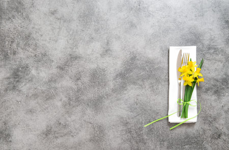 Fork, knife and napkin on table plate with spring flowers decorationの写真素材