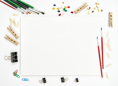 Flat lay with sketchbook, brushes, paper, office supplies on white background. Top viewの写真素材