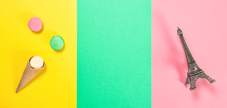 Macaroon cookies on pink green yellow colored background. Macarons french cake in ice cream waffle cone and Eiffel tower Parisの写真素材