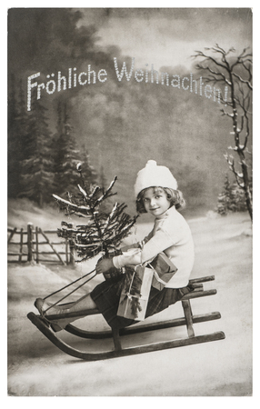 Little girl with sled and Christmas tree. Nostalgic vintage picture with original film grain and scratchesの写真素材
