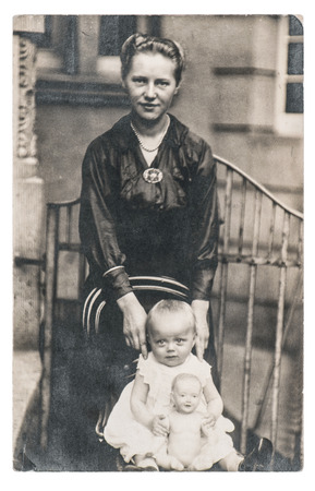 BERLIN, GERMANY - CIRCA 1930: Old photo portrait of mother with baby and doll wearing vintage clothingの写真素材
