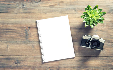 Office workplace flat lay. Paper, old photo camera, coffee, succulent plant. Vintage style toned pictureの写真素材