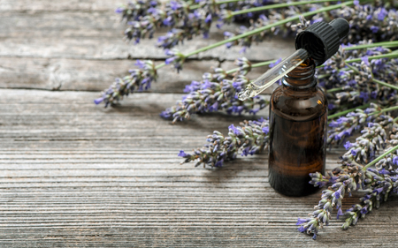 Herbal oil and bunch lavender flower on rustic wooden backgroundの写真素材